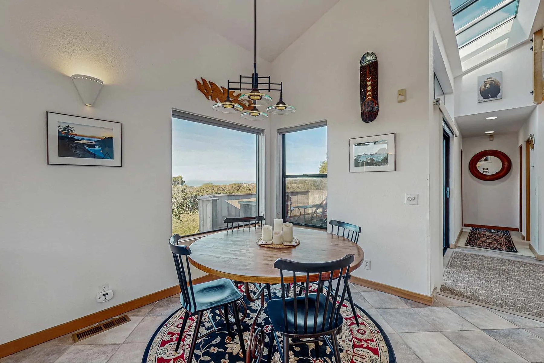A dining area with a round table and windows overlooking the landscape.