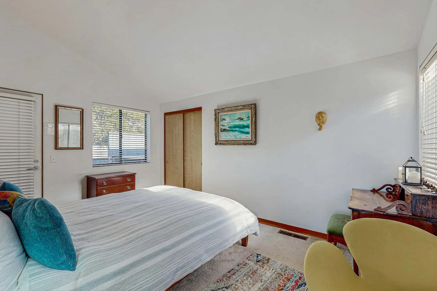 A bedroom with a bed, windows, and a small desk.