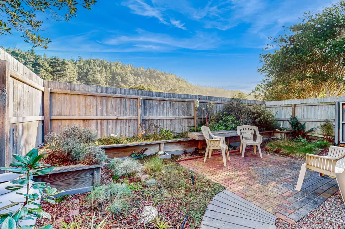 A fenced garden patio with brick paving and outdoor seating.