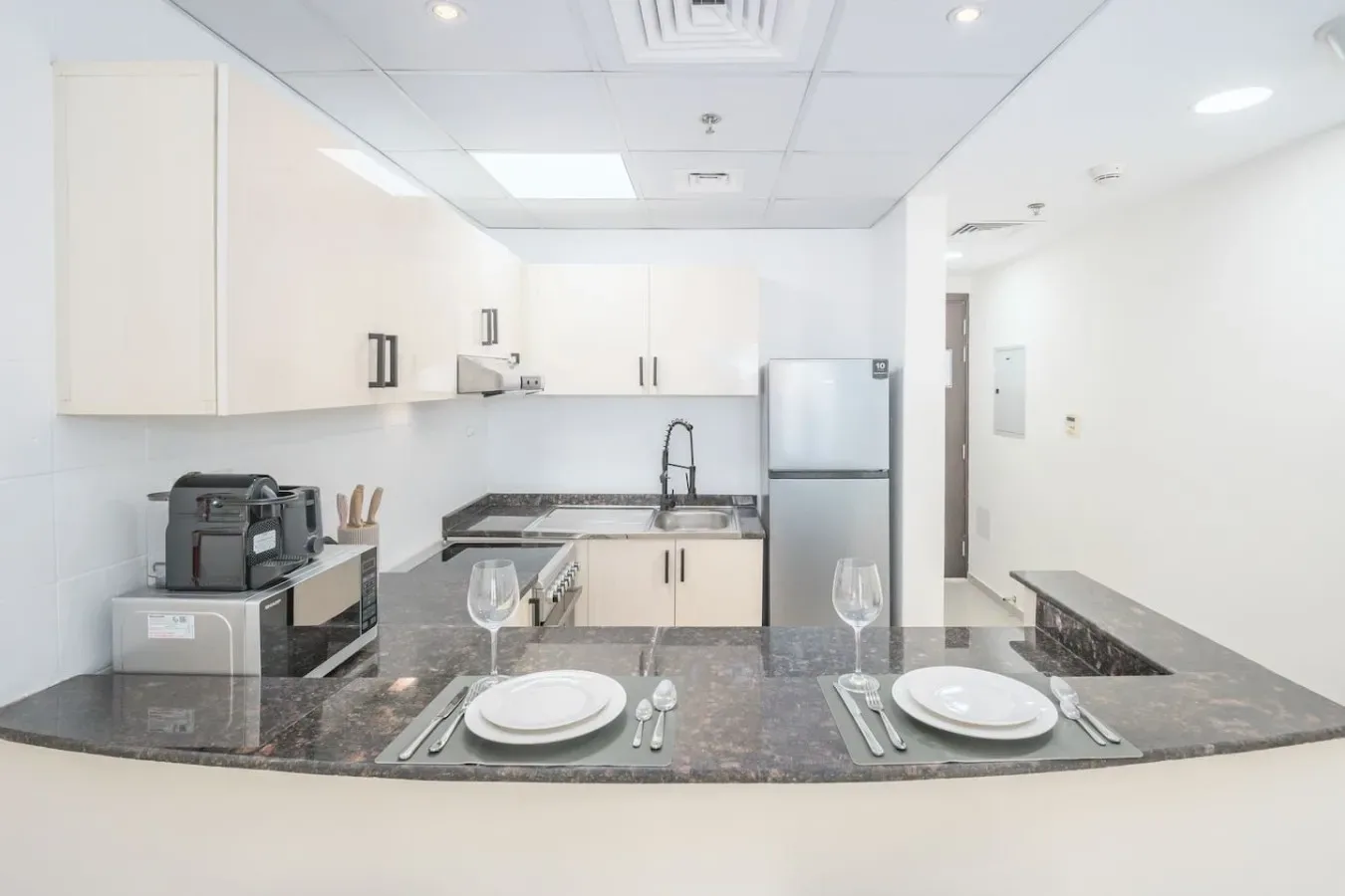 A bright kitchen with a counter set with plates and cutlery.