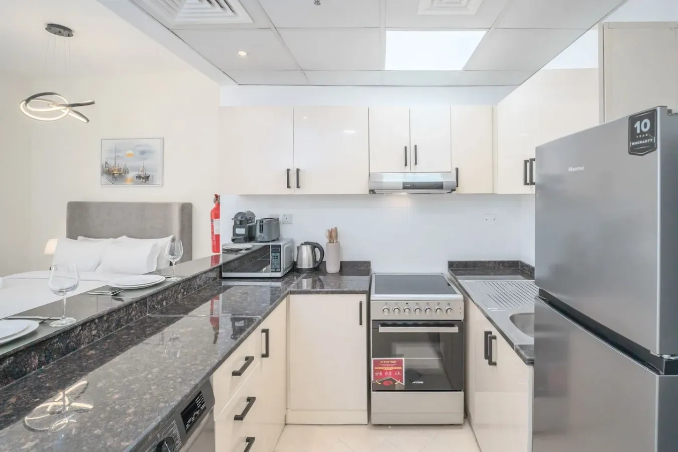 A bright kitchen with white cabinets, dark countertops, and stainless steel appliances.