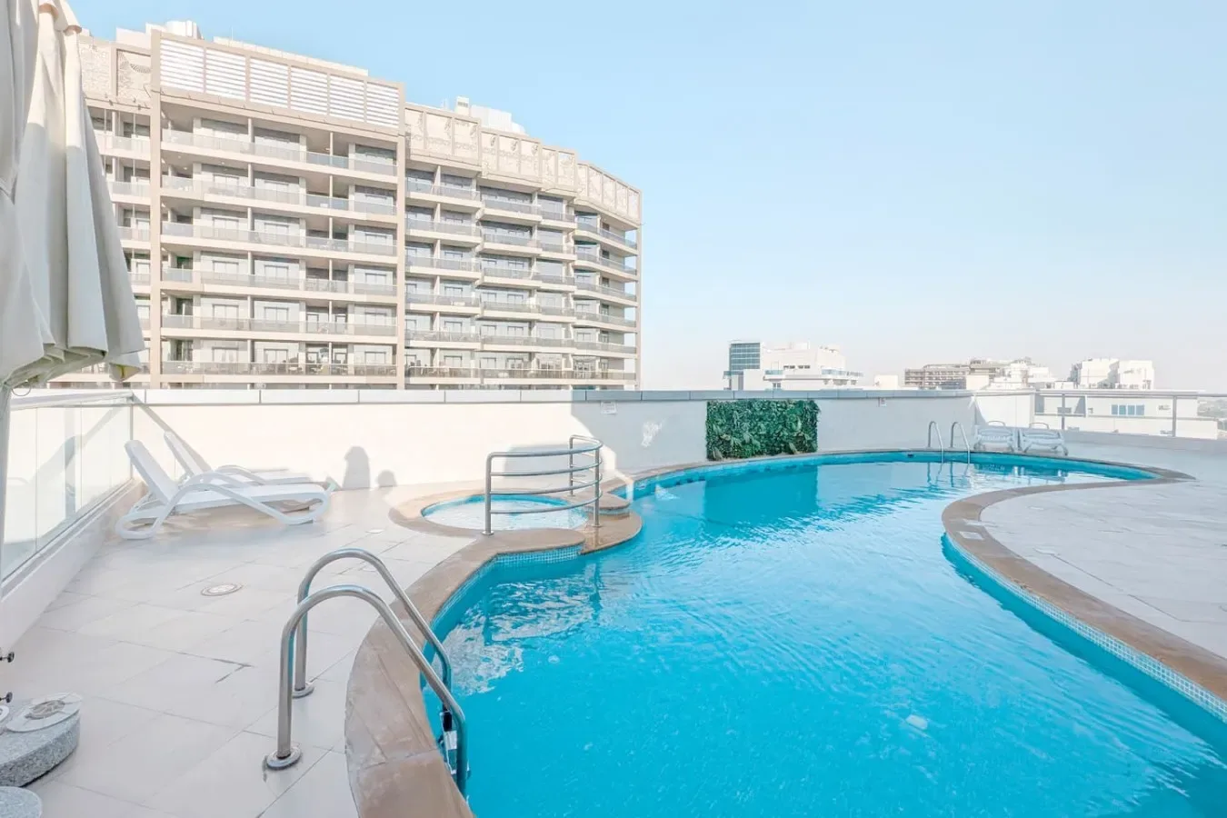 A rooftop swimming pool beside a modern high-rise building.