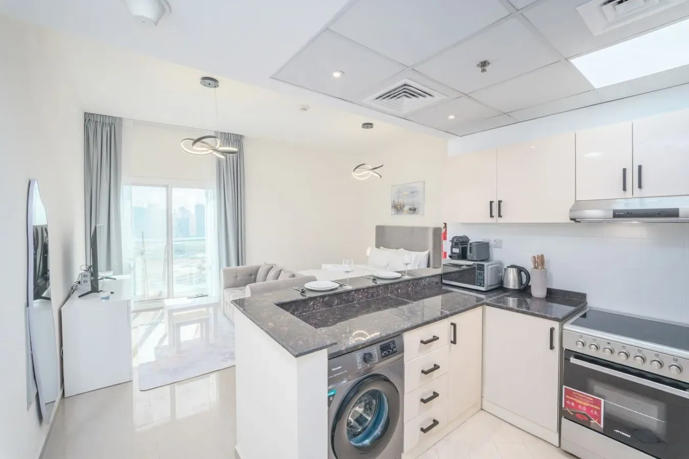 A bright modern kitchen with dark countertops and a washing machine.