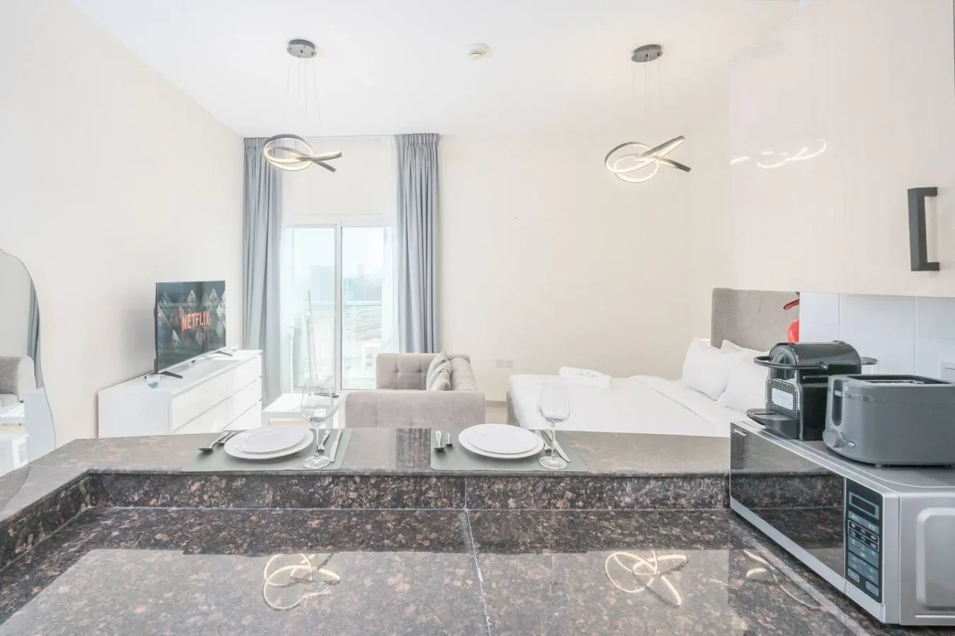 A bright open-plan living and dining area with a kitchen counter in the foreground.