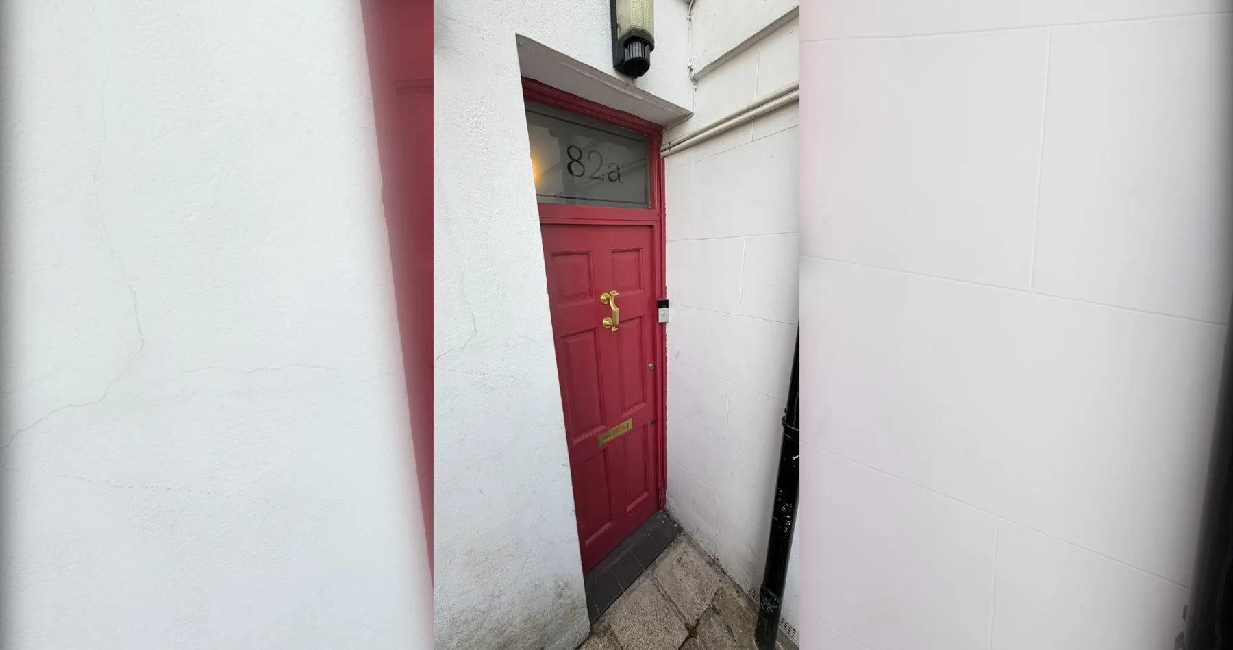 A red entrance door set between white walls.
