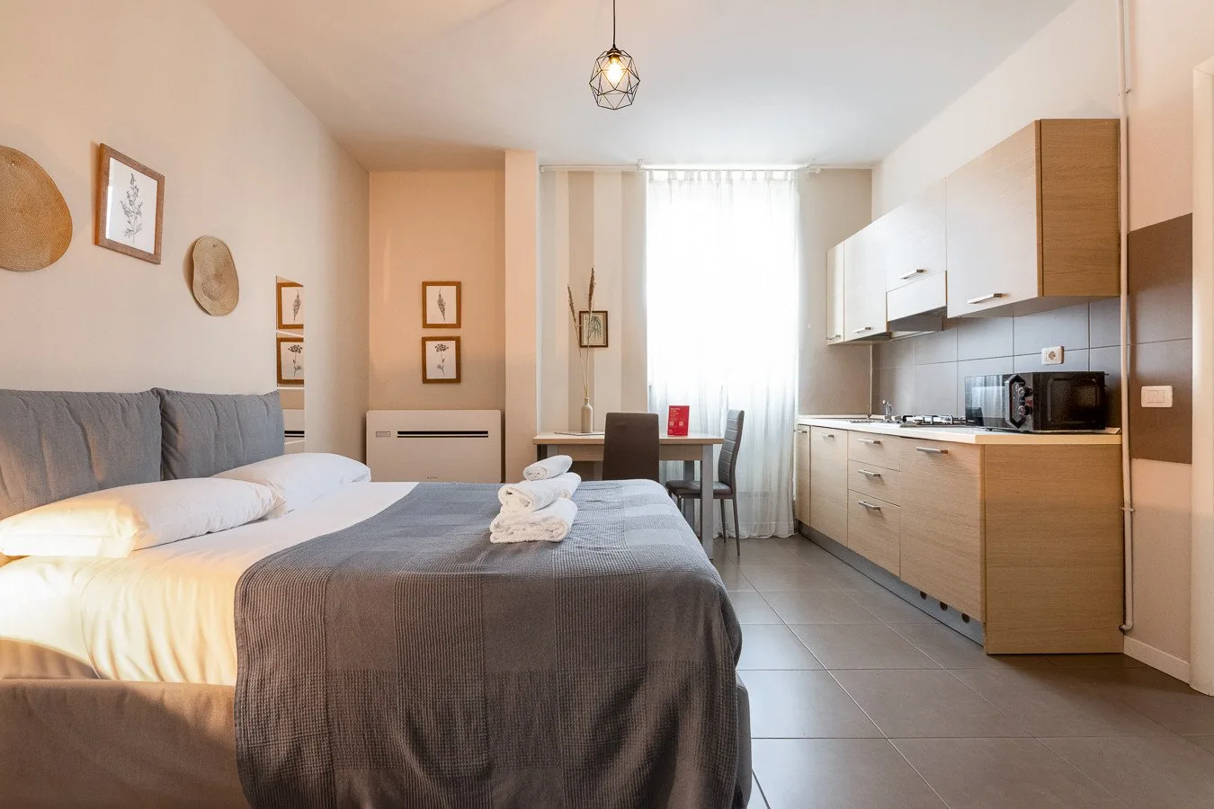 Dormitorio con cocina pequeña y una mesa de comedor junto a la ventana.