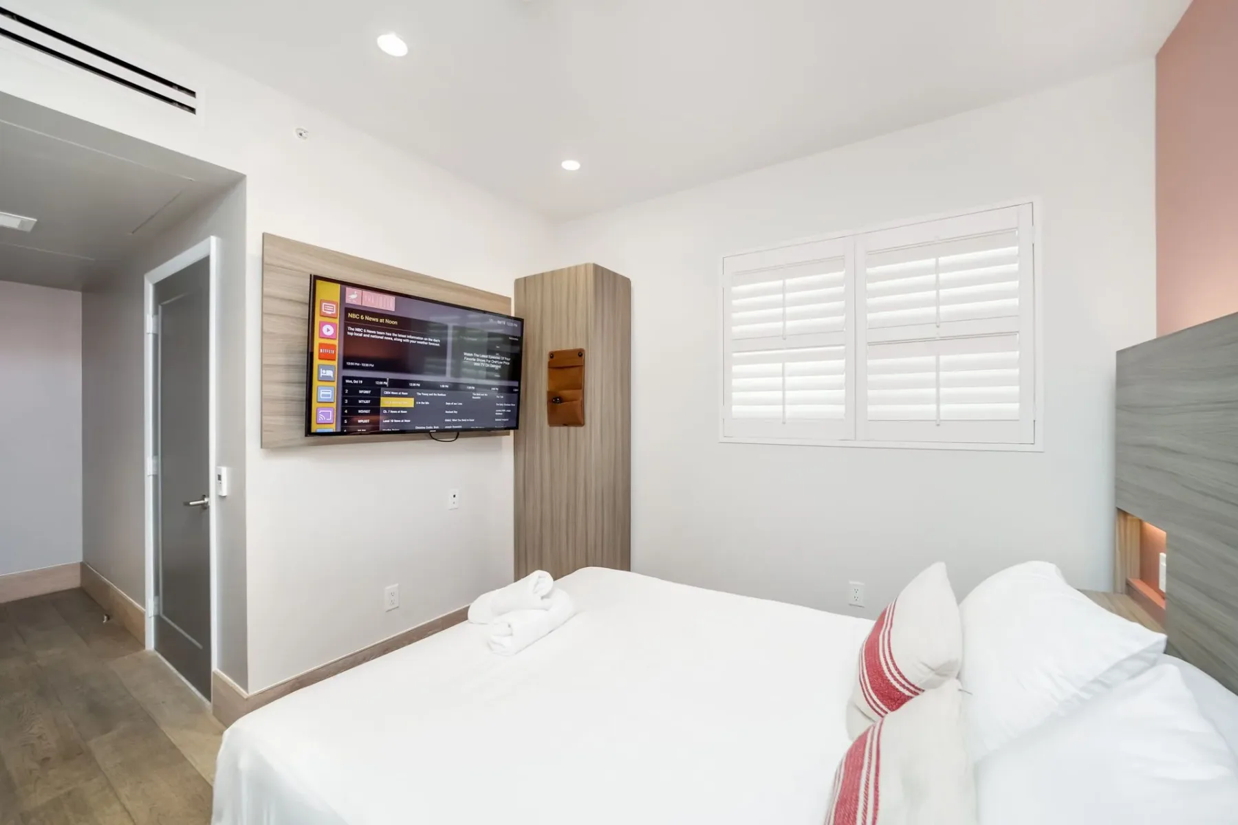 Petite bedroom with a bed, TV, closet, and shuttered window.