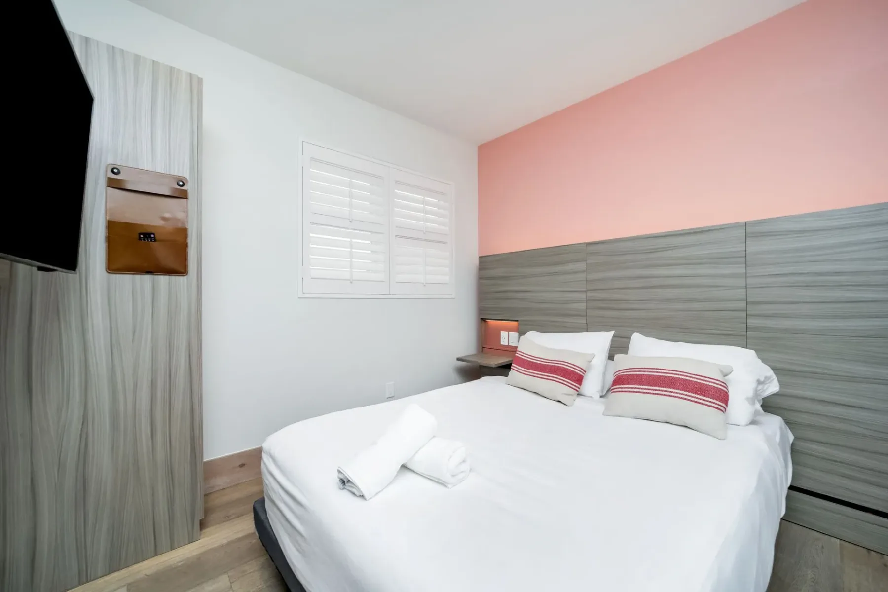 Petite bedroom with a bed, TV, and shuttered window.