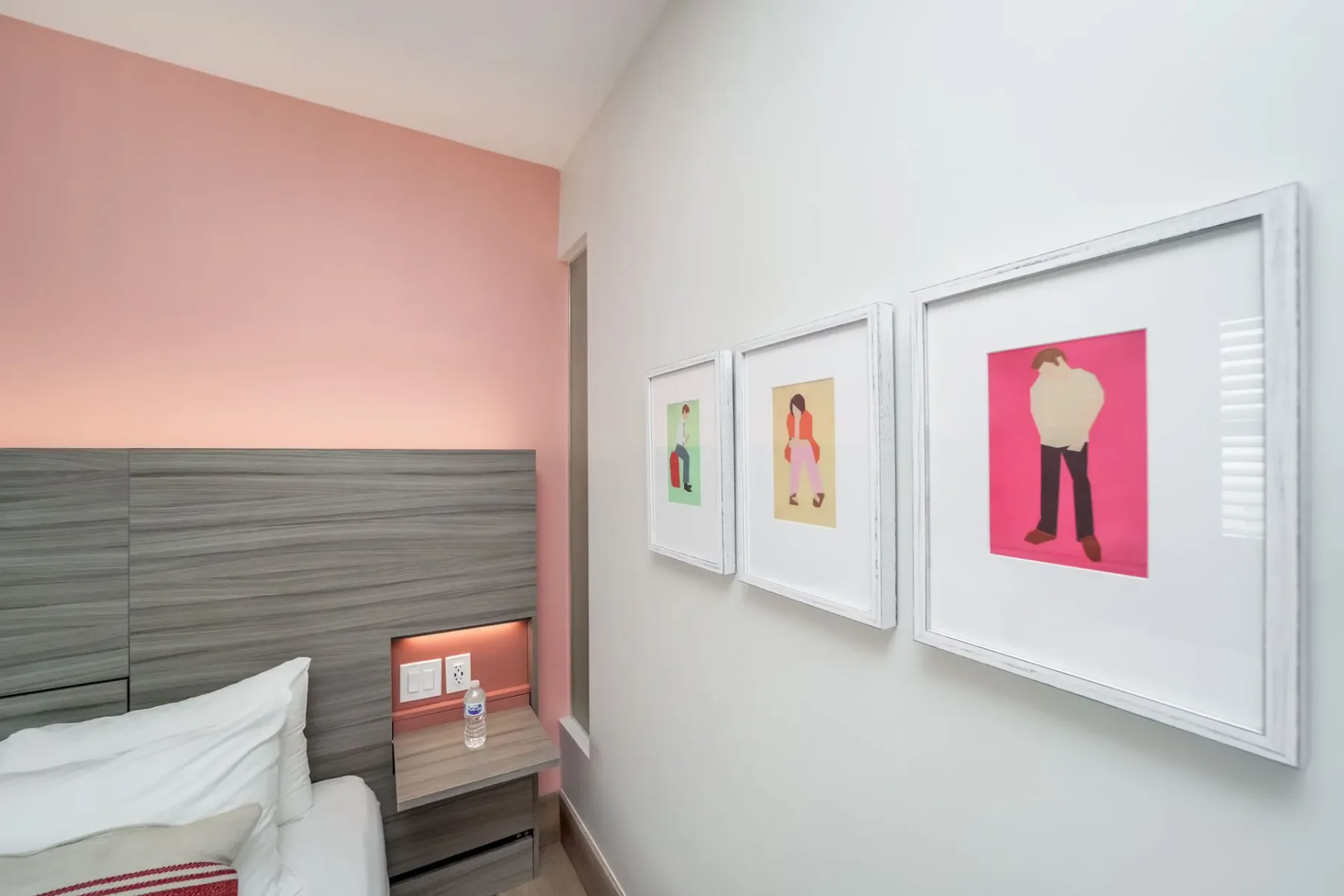 Serene Superior bedroom corner with a bed, nightstand, framed art, and pink and white walls.