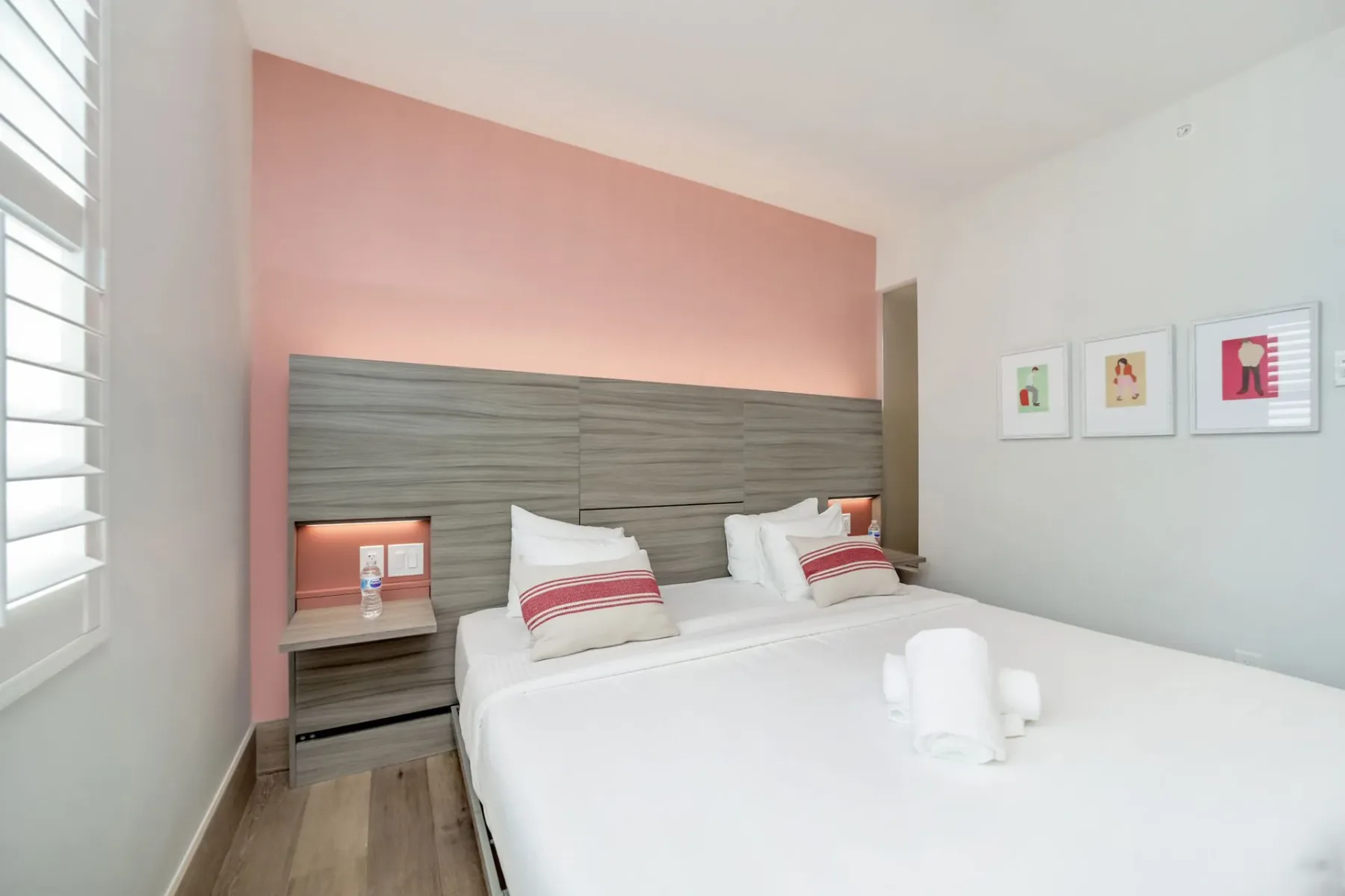 Serene Superior bedroom with a double bed, pink accent wall, and framed prints.