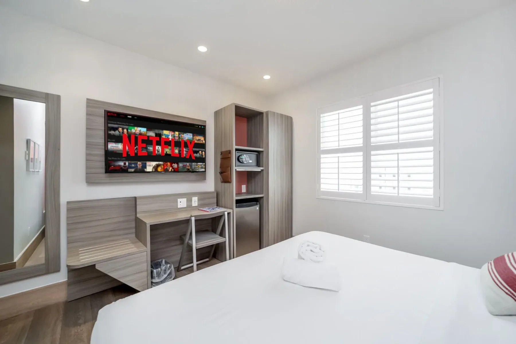 Serene Superior room with a bed, TV, desk, window with blinds, and storage cabinet.