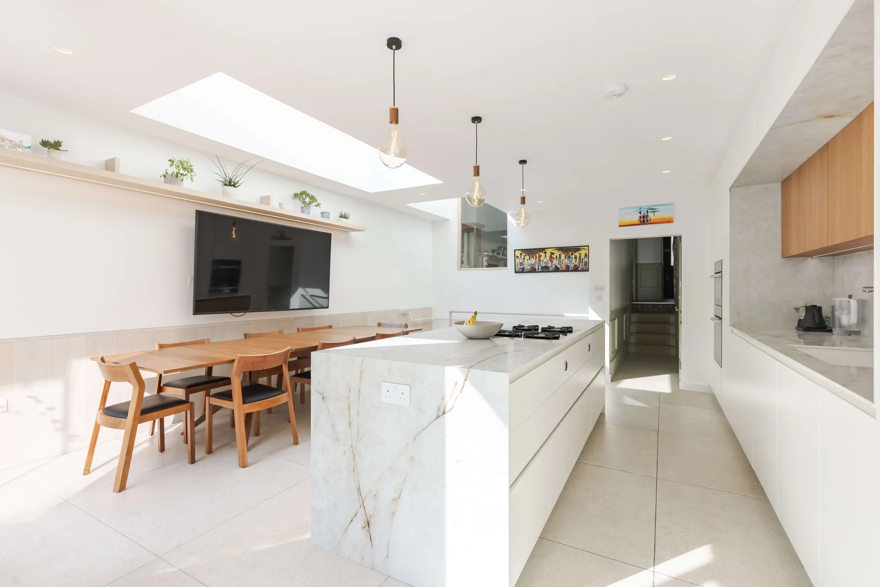 Una cocina y comedor luminosos con una isla central y una mesa de madera.