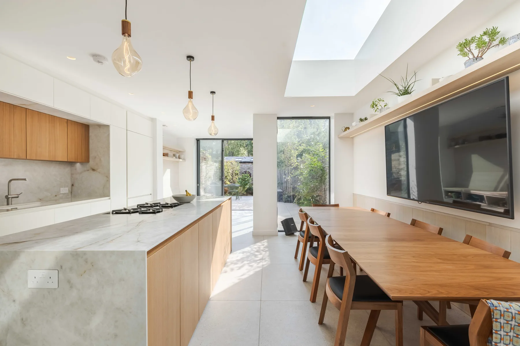 Una luminosa cocina y comedor de concepto abierto con una larga mesa de madera.