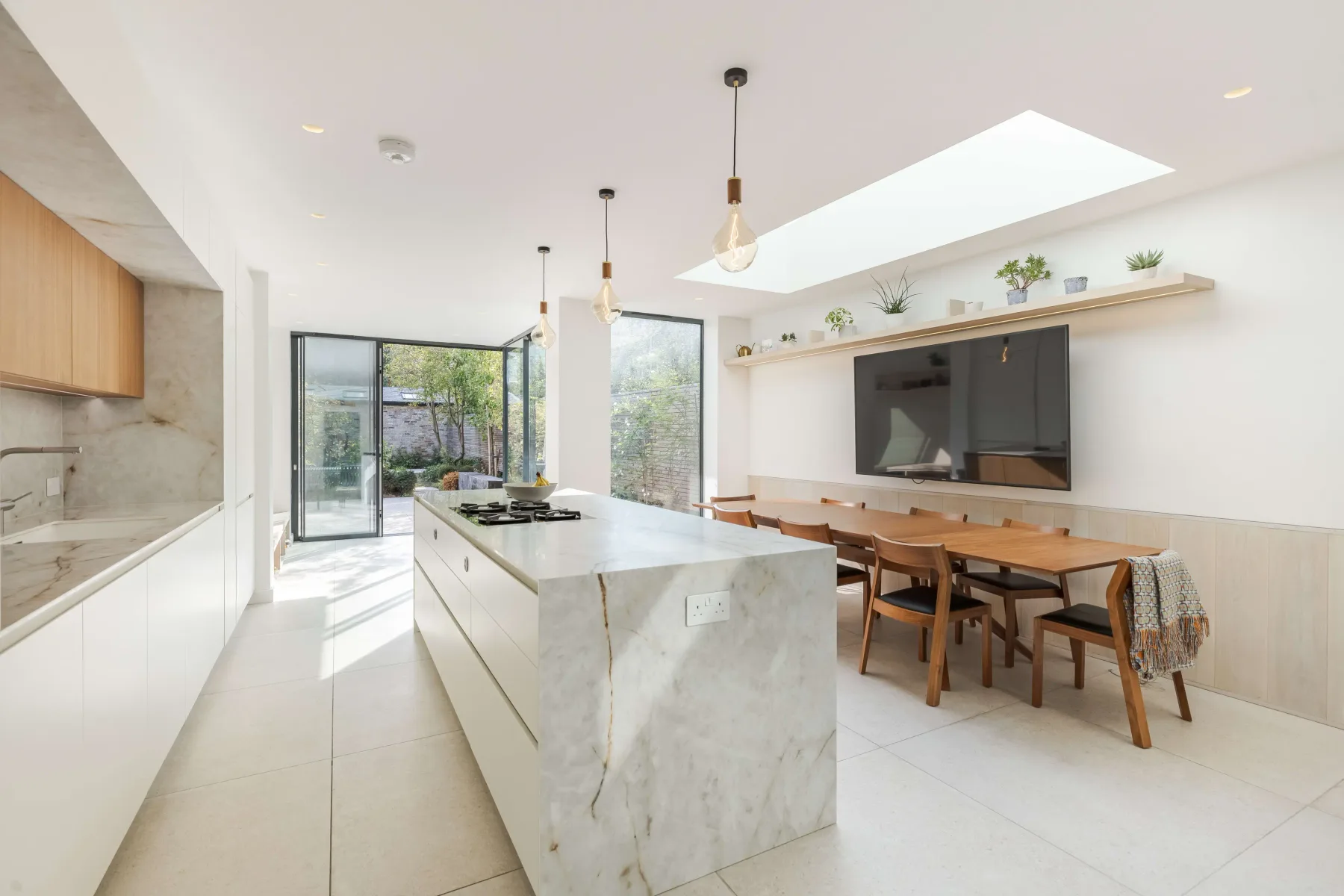 Una cocina moderna y luminosa con una isla de mármol y una mesa de comedor.