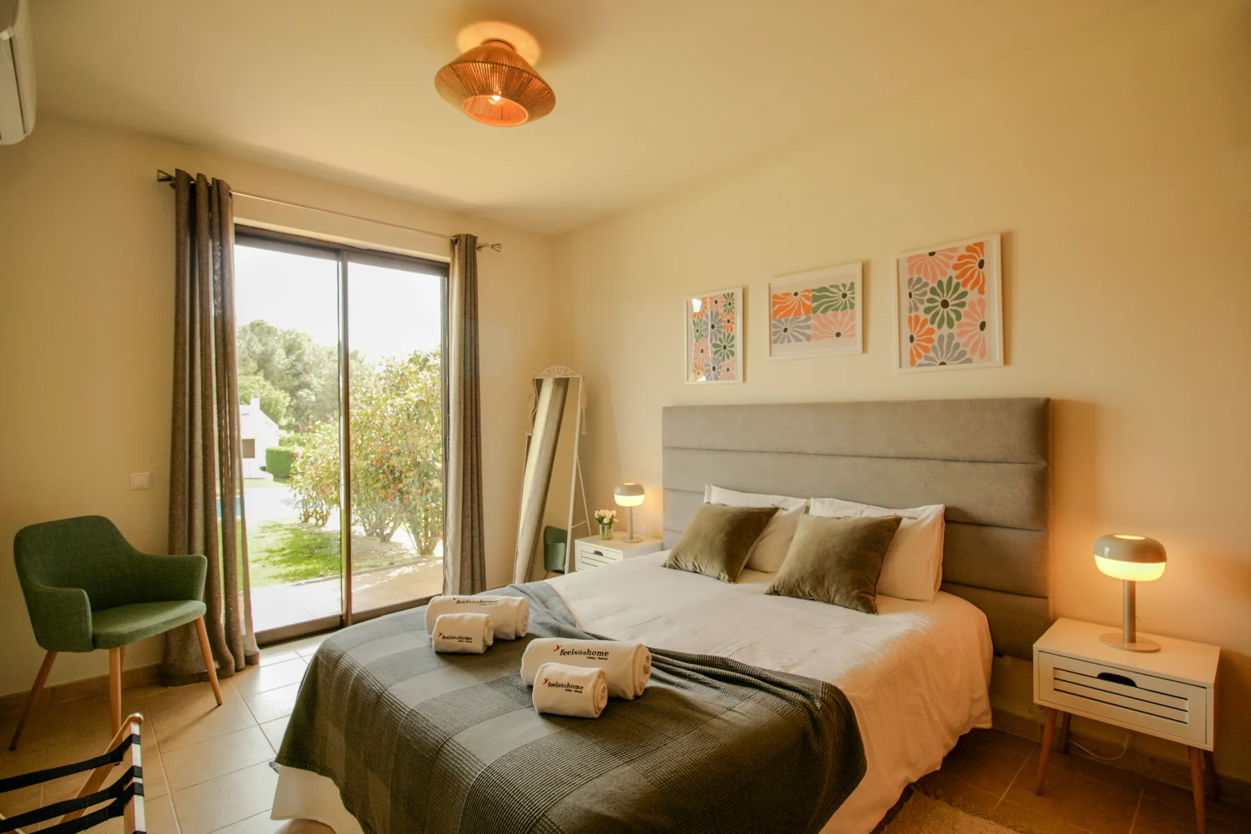 A bedroom with a neatly made bed and glass doors opening onto greenery.