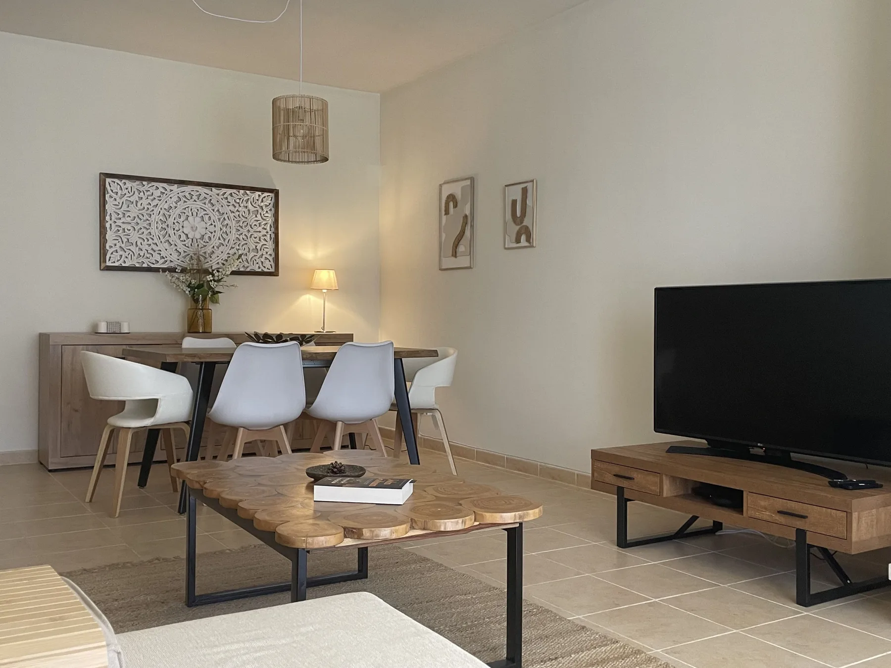 A dining and living area with a table, seating, and a television.