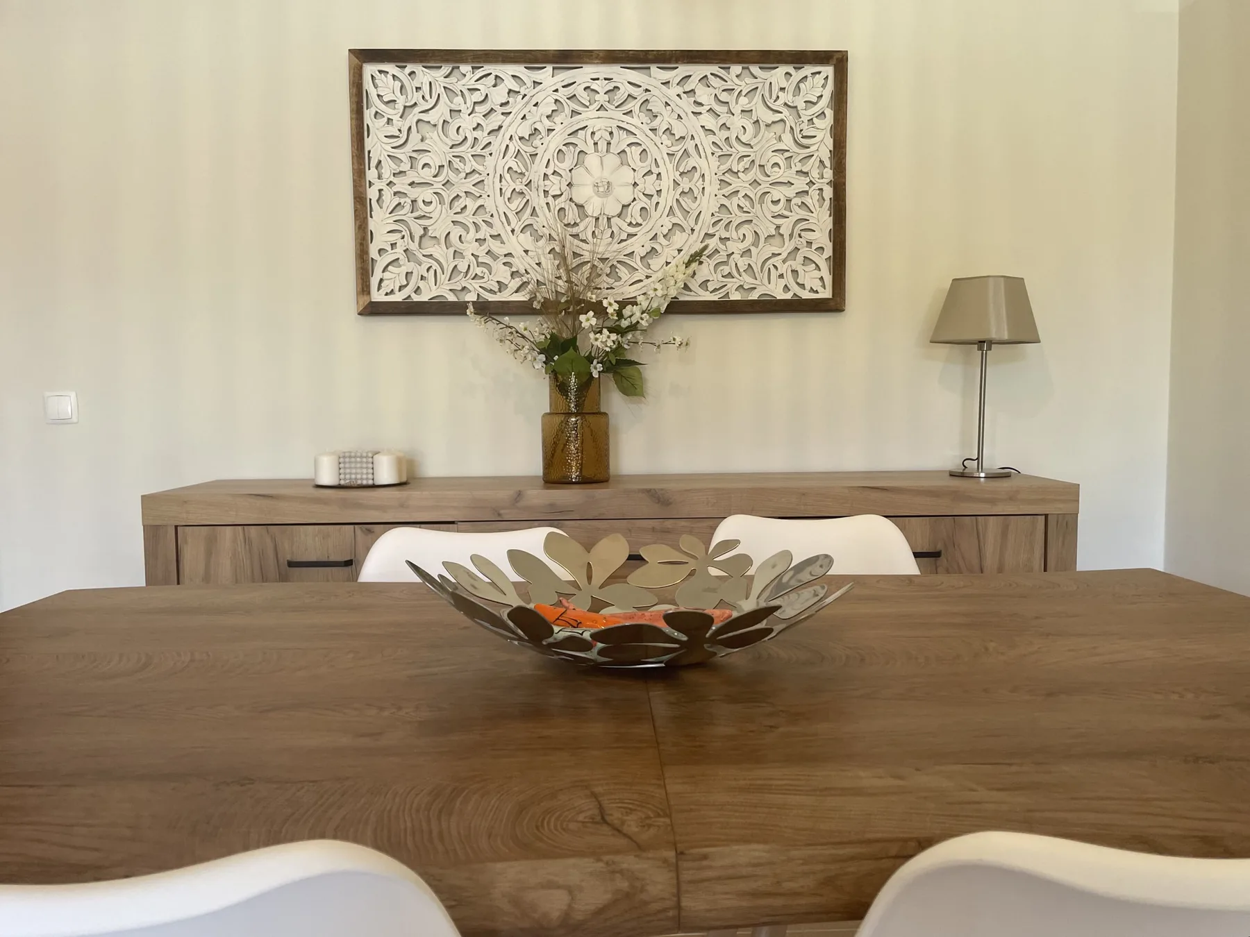A dining area with a wooden table and decorative wall art.