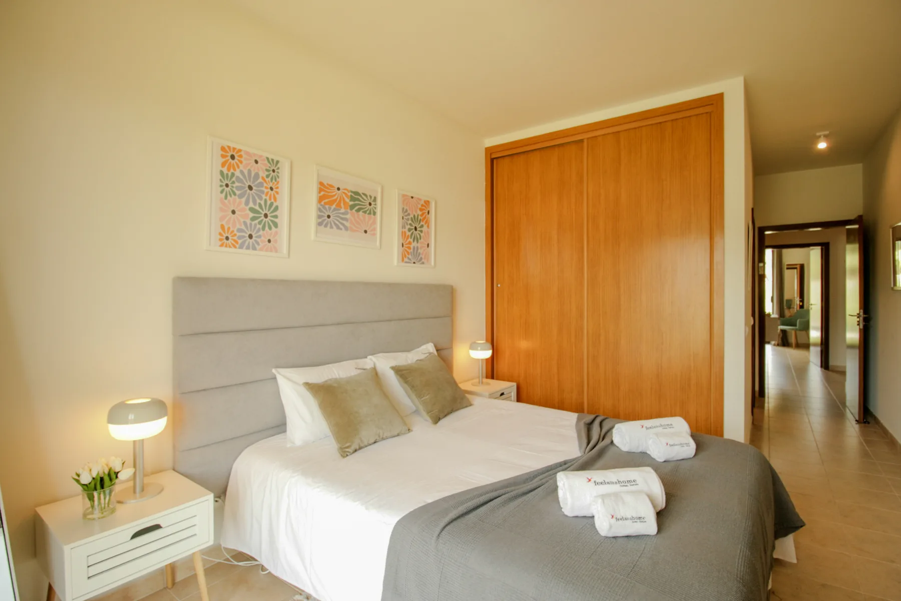 A bedroom with a neatly made bed and a large wooden wardrobe.