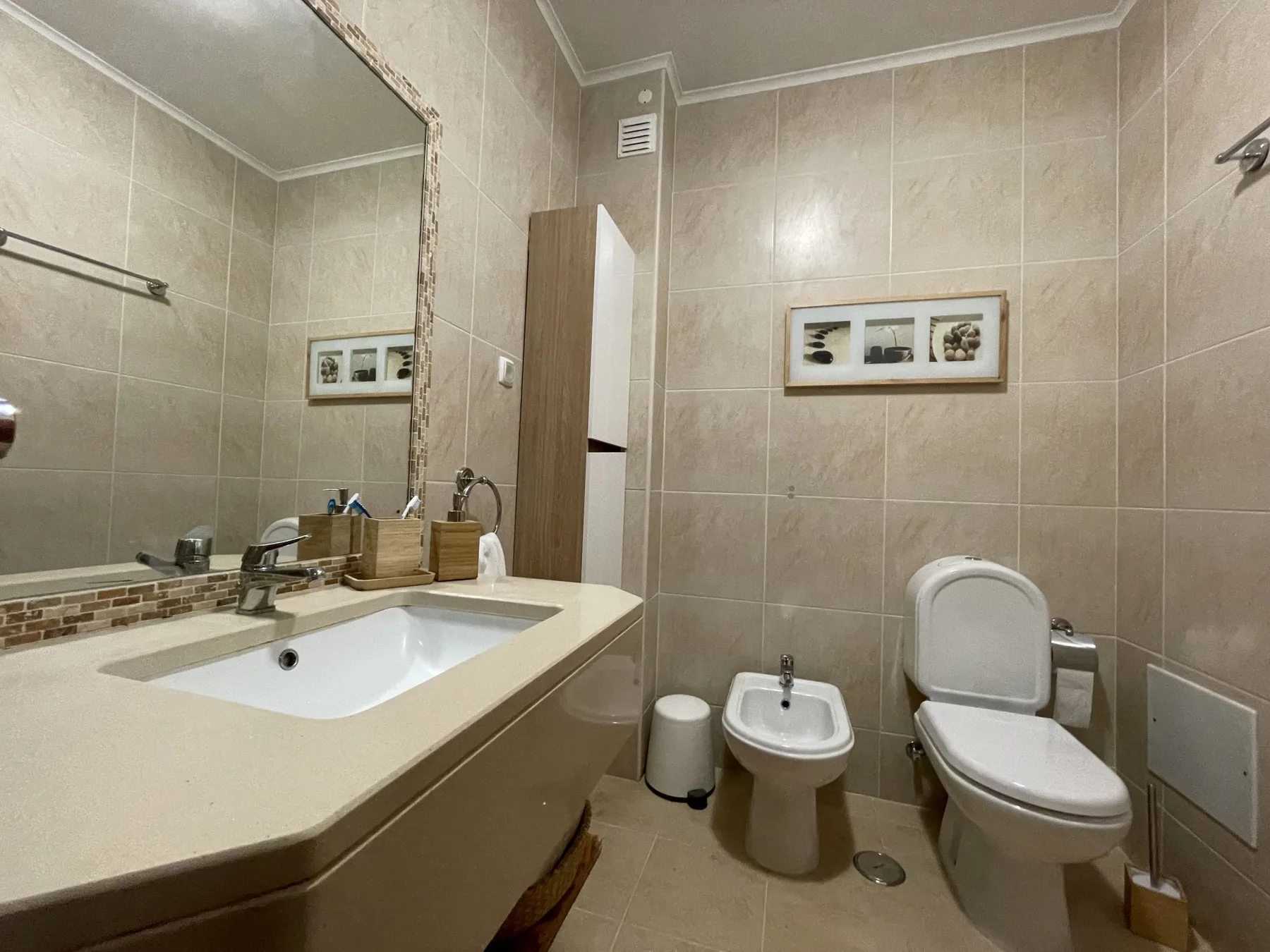 A bathroom with a sink, toilet, and bidet.