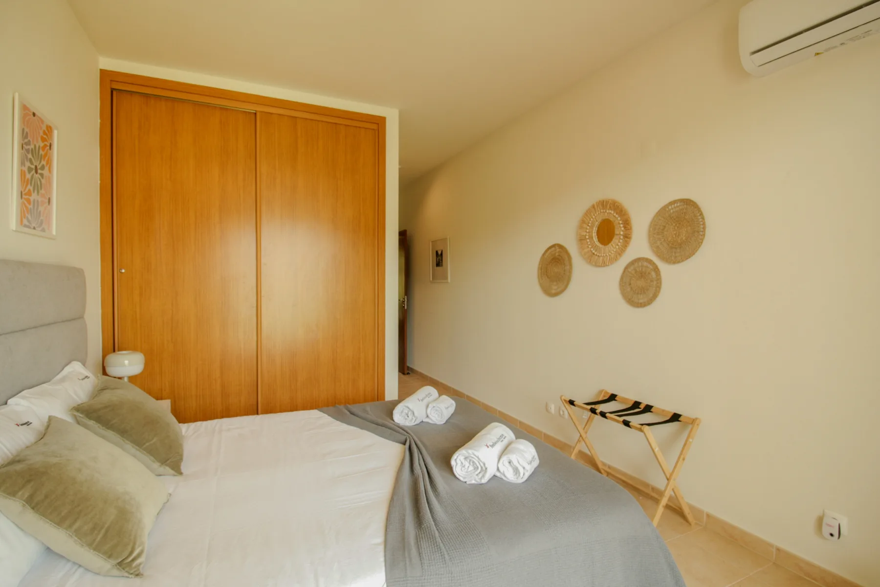A bedroom with a bed, wooden wardrobe, and round wall decorations.