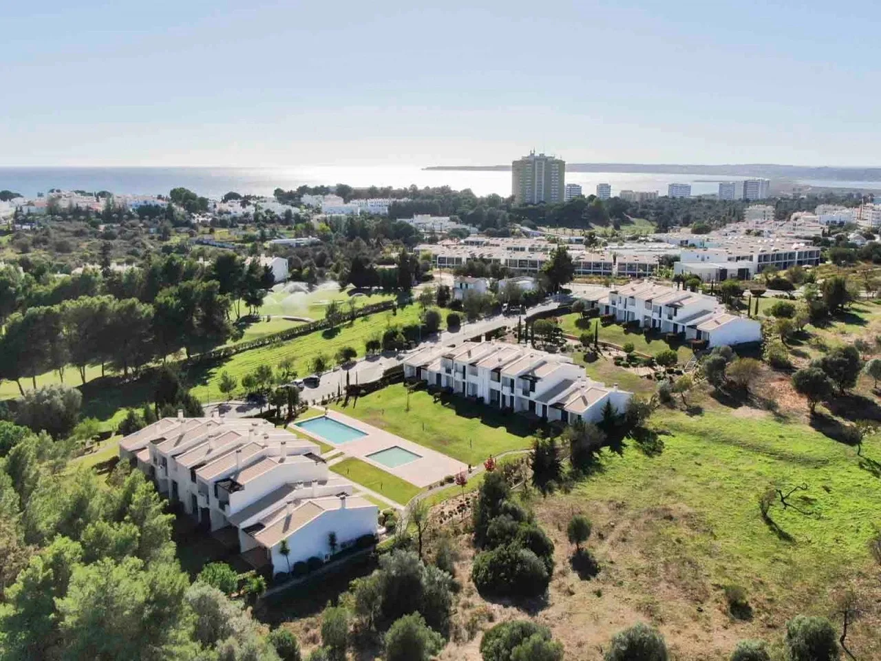 Aerial view of low-rise buildings among green grounds and trees.