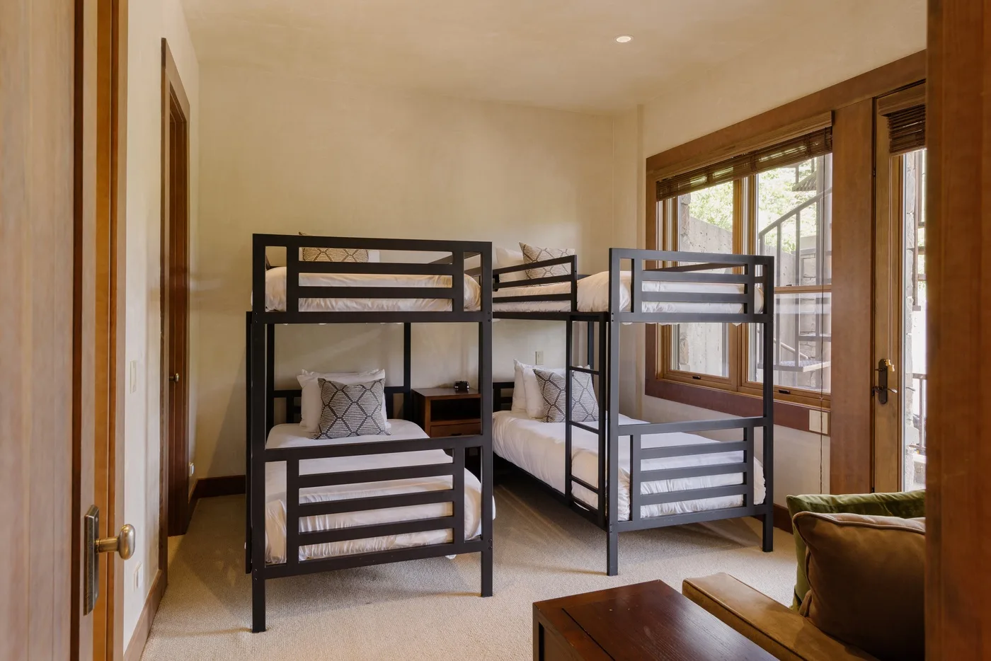 A bedroom with dark bunk beds beside large windows.