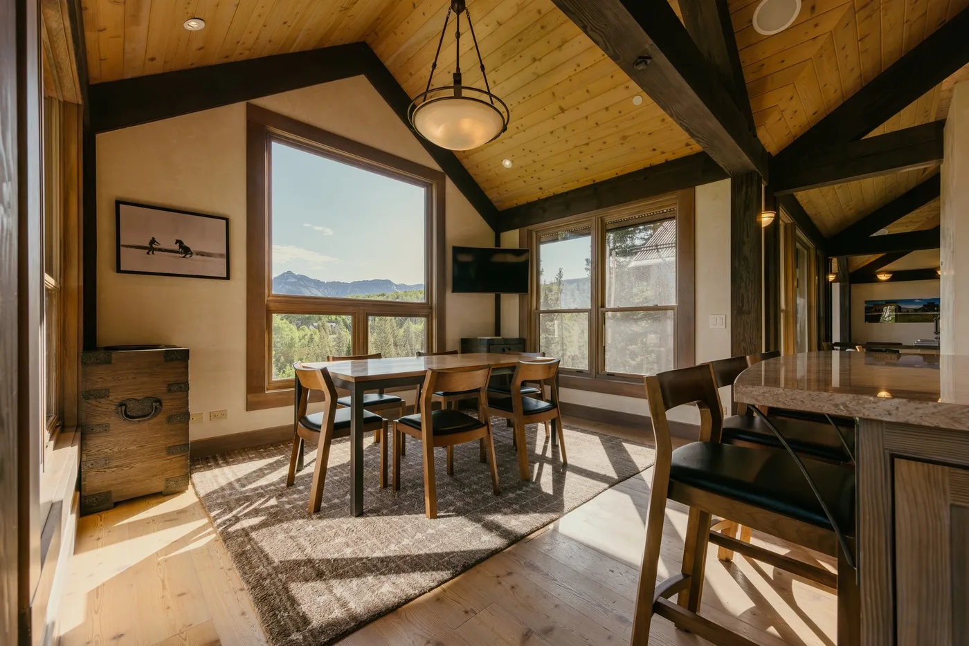 A dining area with a wooden table beneath a high, sloped ceiling.
