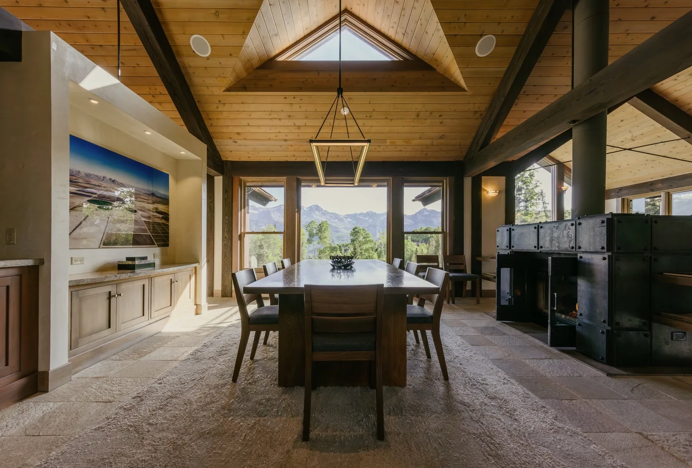 A dining area with a long table beneath a high wooden ceiling.