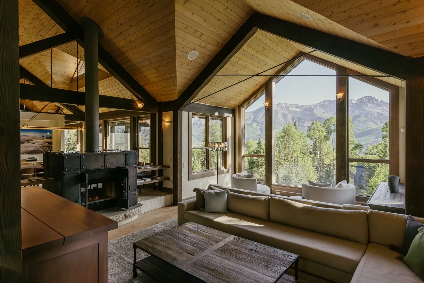 A living room with seating and large windows overlooking a mountain landscape.