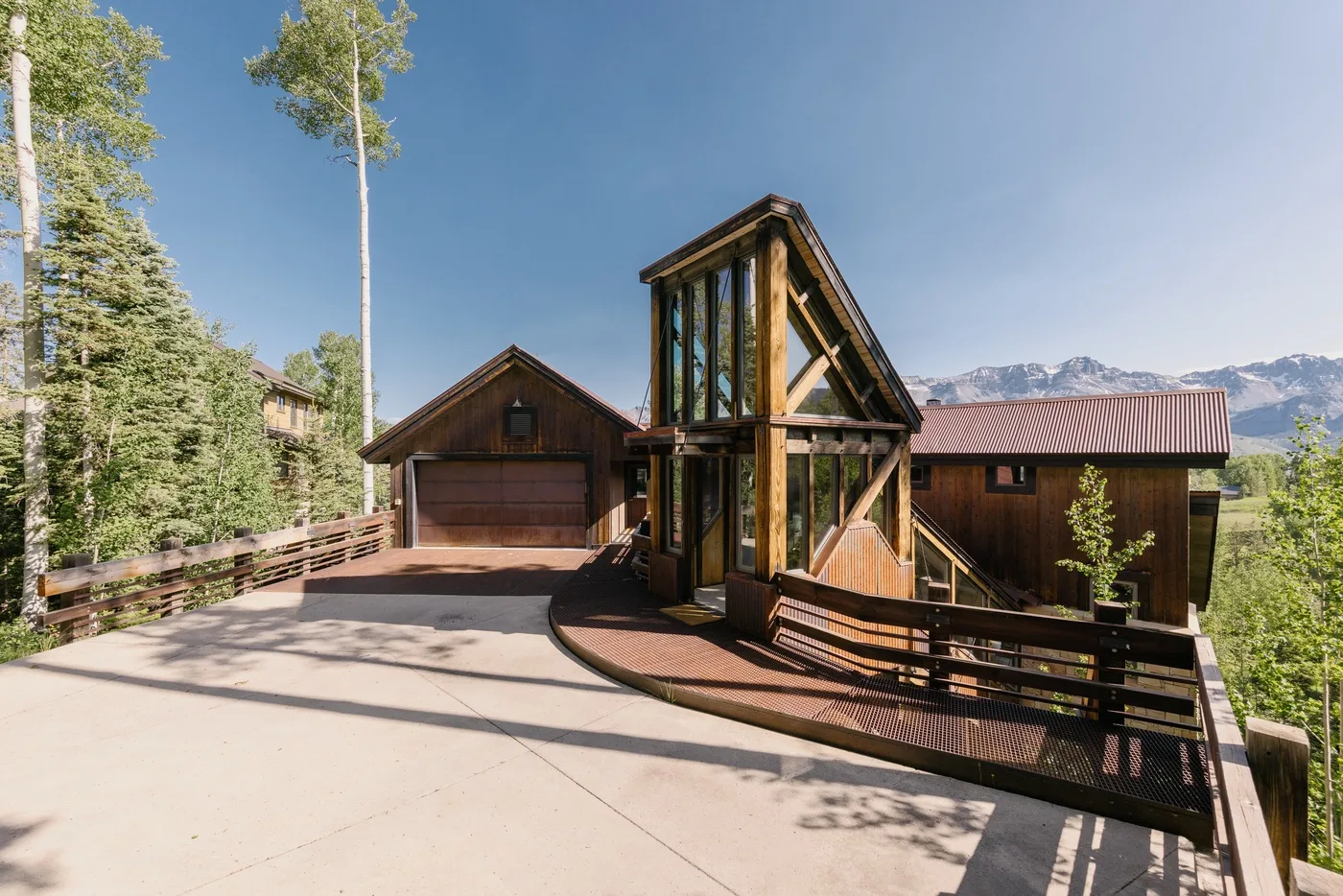 A mountain home with a timber-framed entrance and a wide paved driveway.