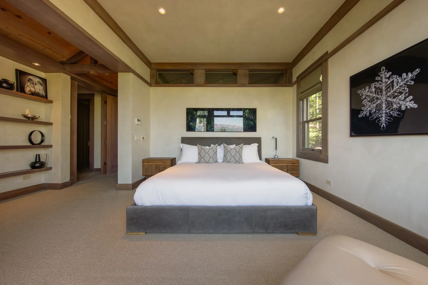 A bedroom with a neatly made bed beneath a window.