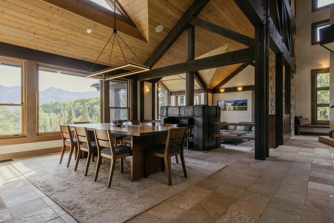 A dining area with a large wooden table beneath a vaulted timber ceiling.