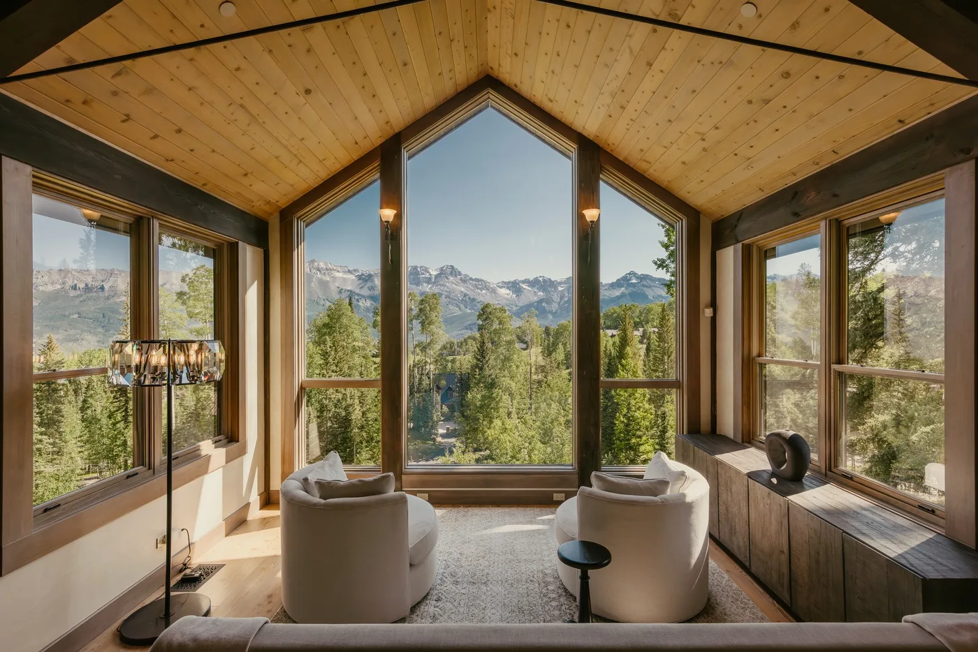 A bright living room with seating facing large windows and a mountain view.