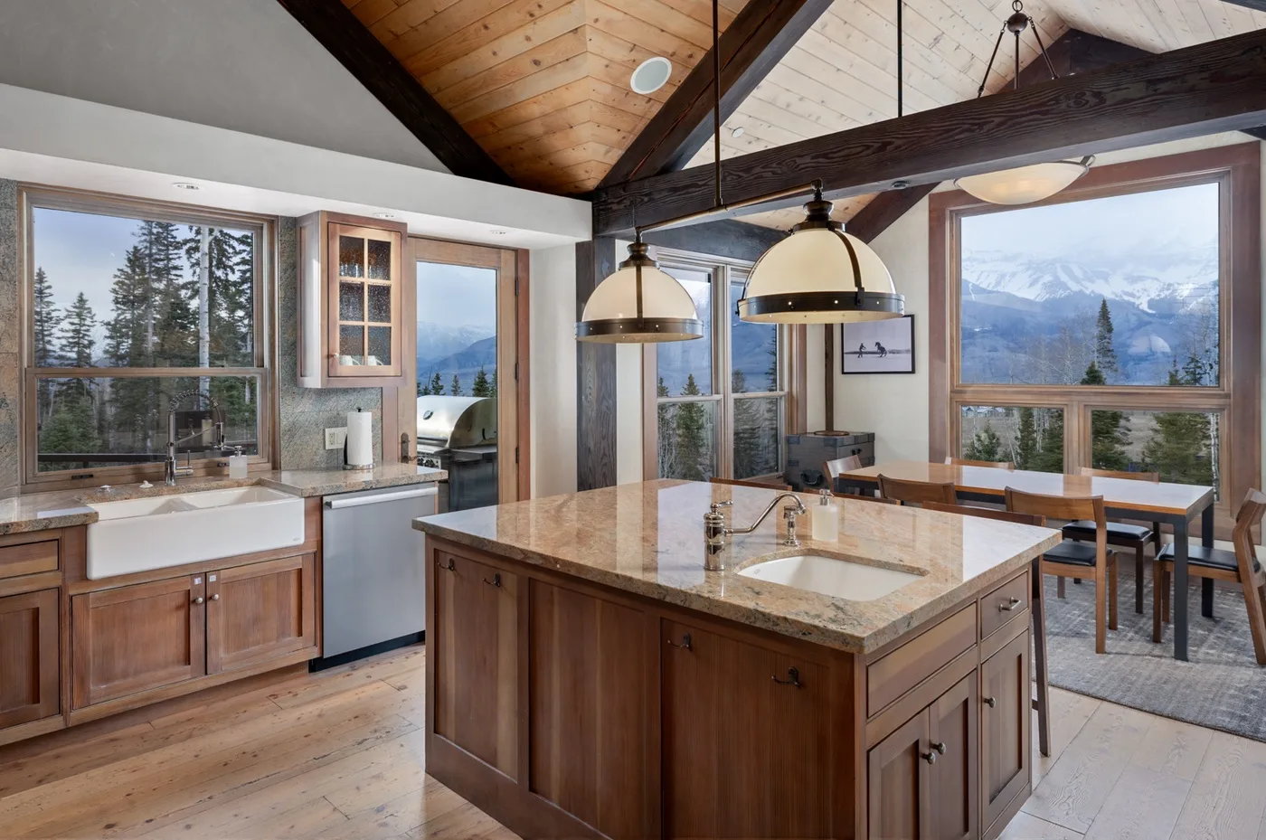 A spacious kitchen with a central island, pendant lights, and large windows overlooking mountains.