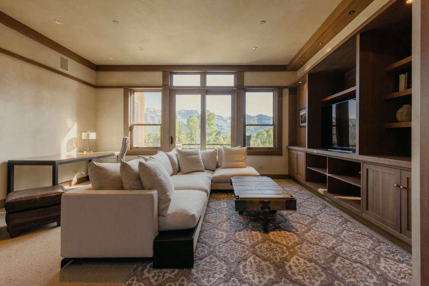 A living room with seating arranged beside large windows overlooking a mountain landscape.