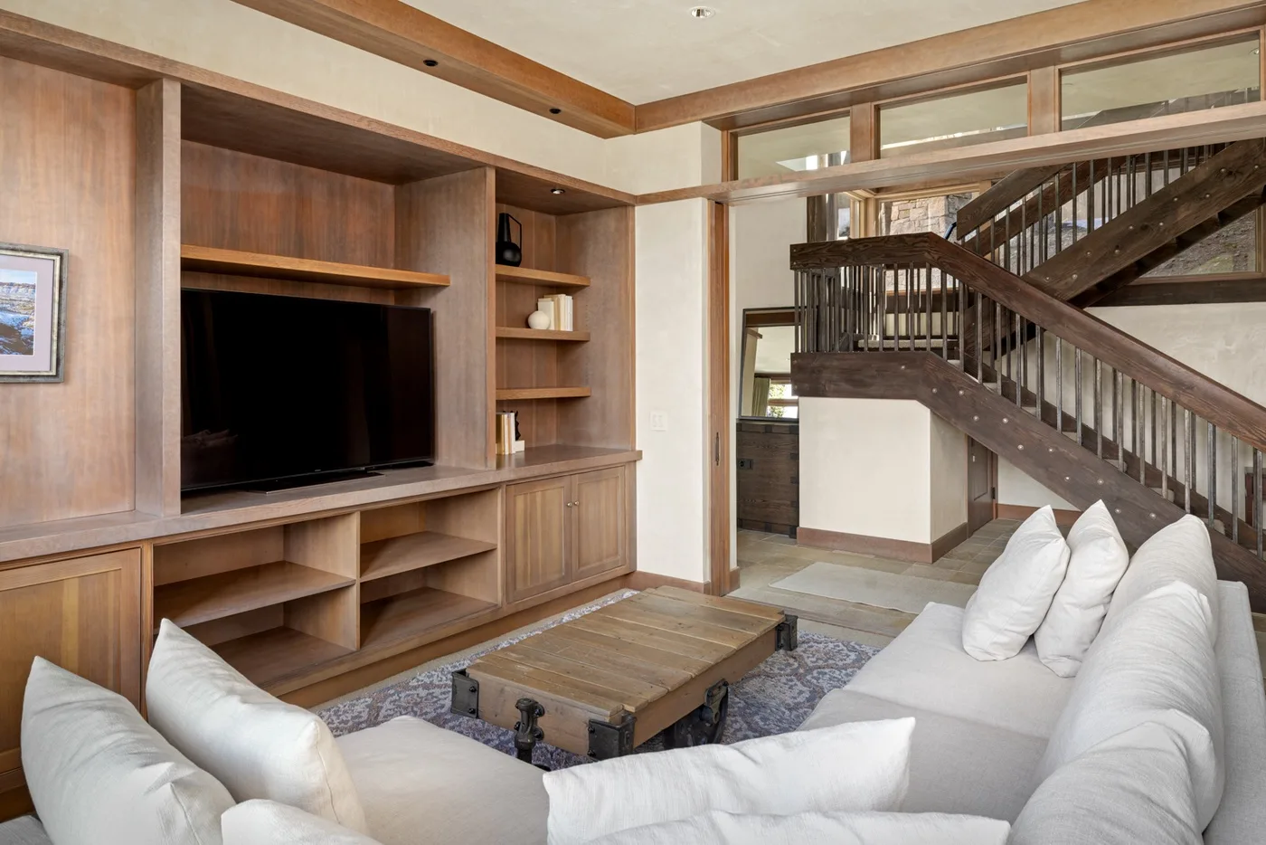 A living room with a built-in entertainment unit, seating, and a staircase.
