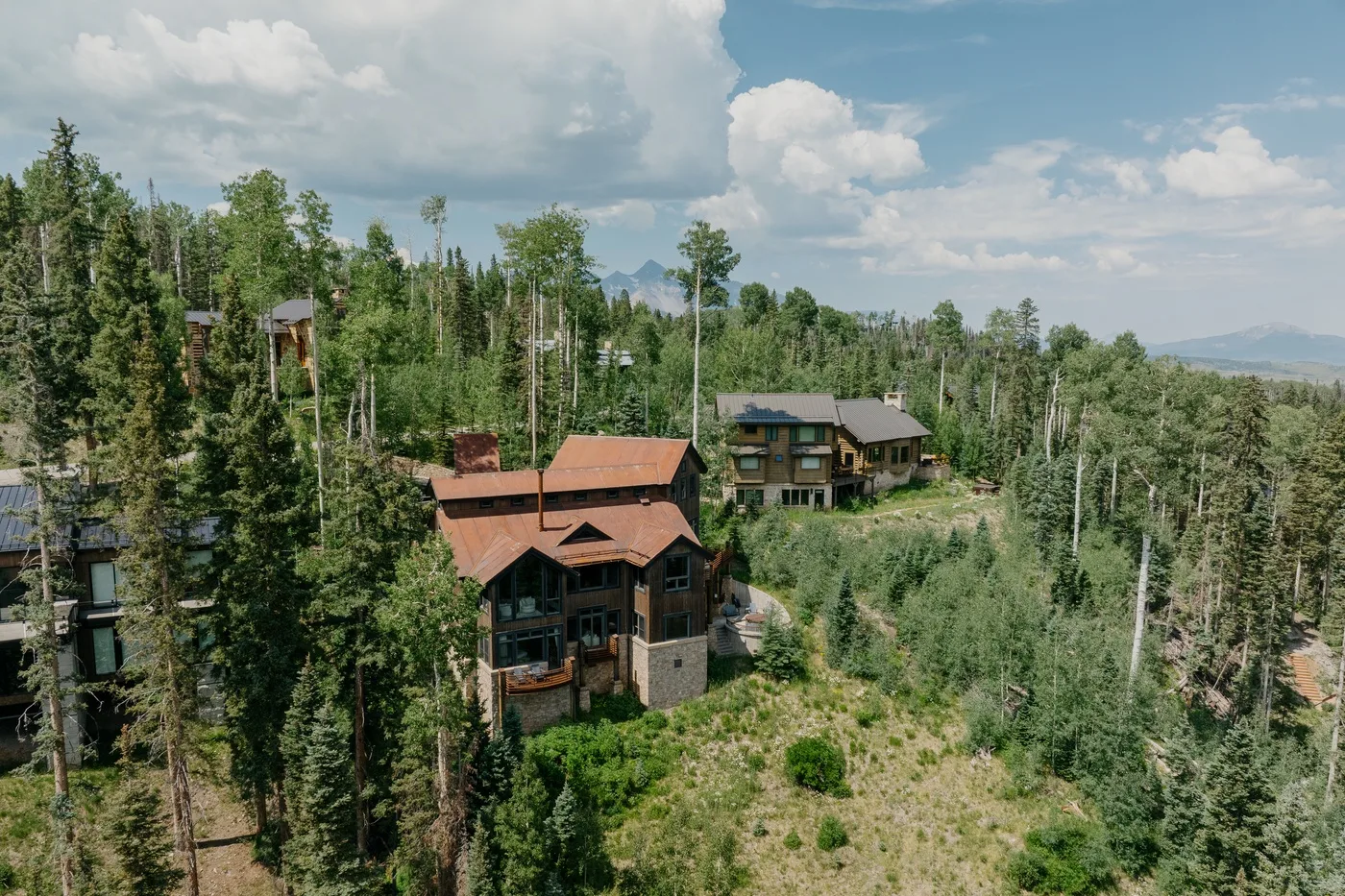 Aerial view of cabins among trees on a wooded hillside.