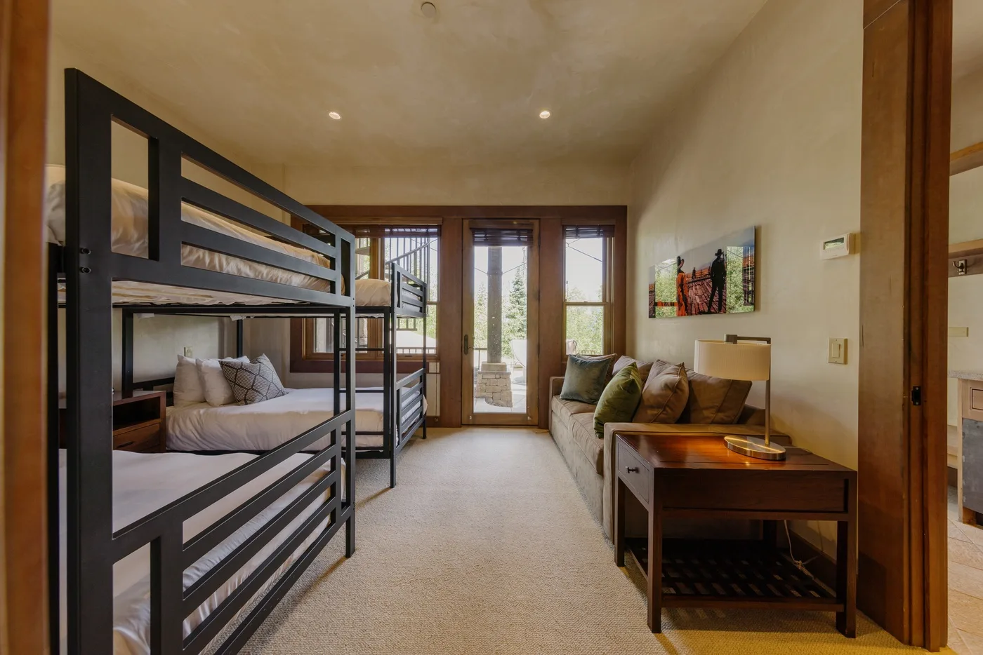 A bedroom with bunk beds, a sitting area, and glass doors opening to a balcony.