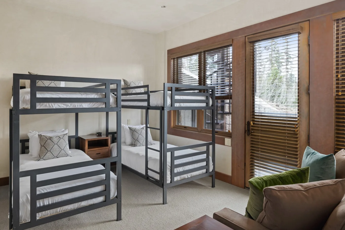 A bedroom with two bunk beds and windows with wooden blinds.