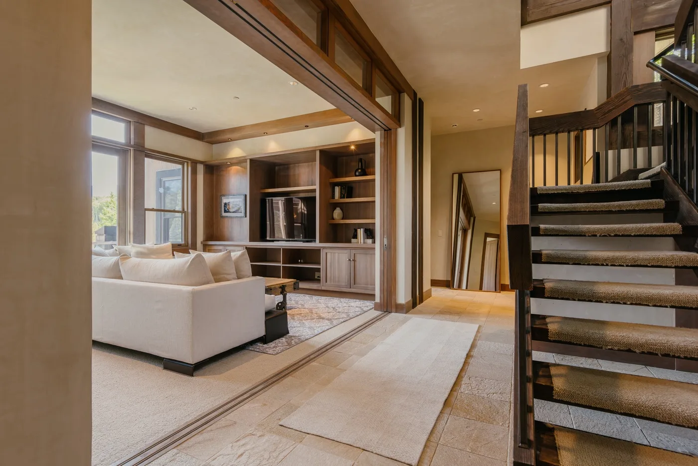 A living room with light-colored seating and built-in shelving beside a staircase.