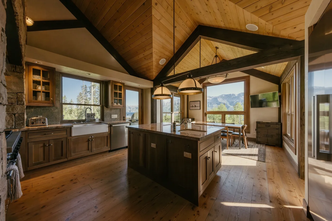 A spacious kitchen with a central island, wooden cabinetry, and large windows.