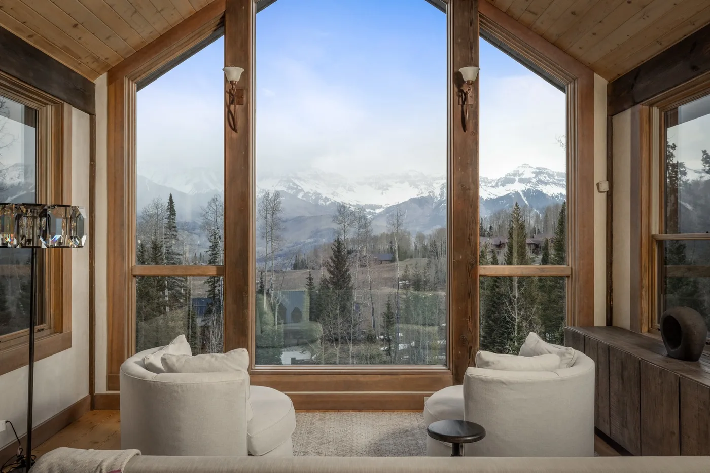 A living area with seating faces large windows overlooking a mountain landscape.