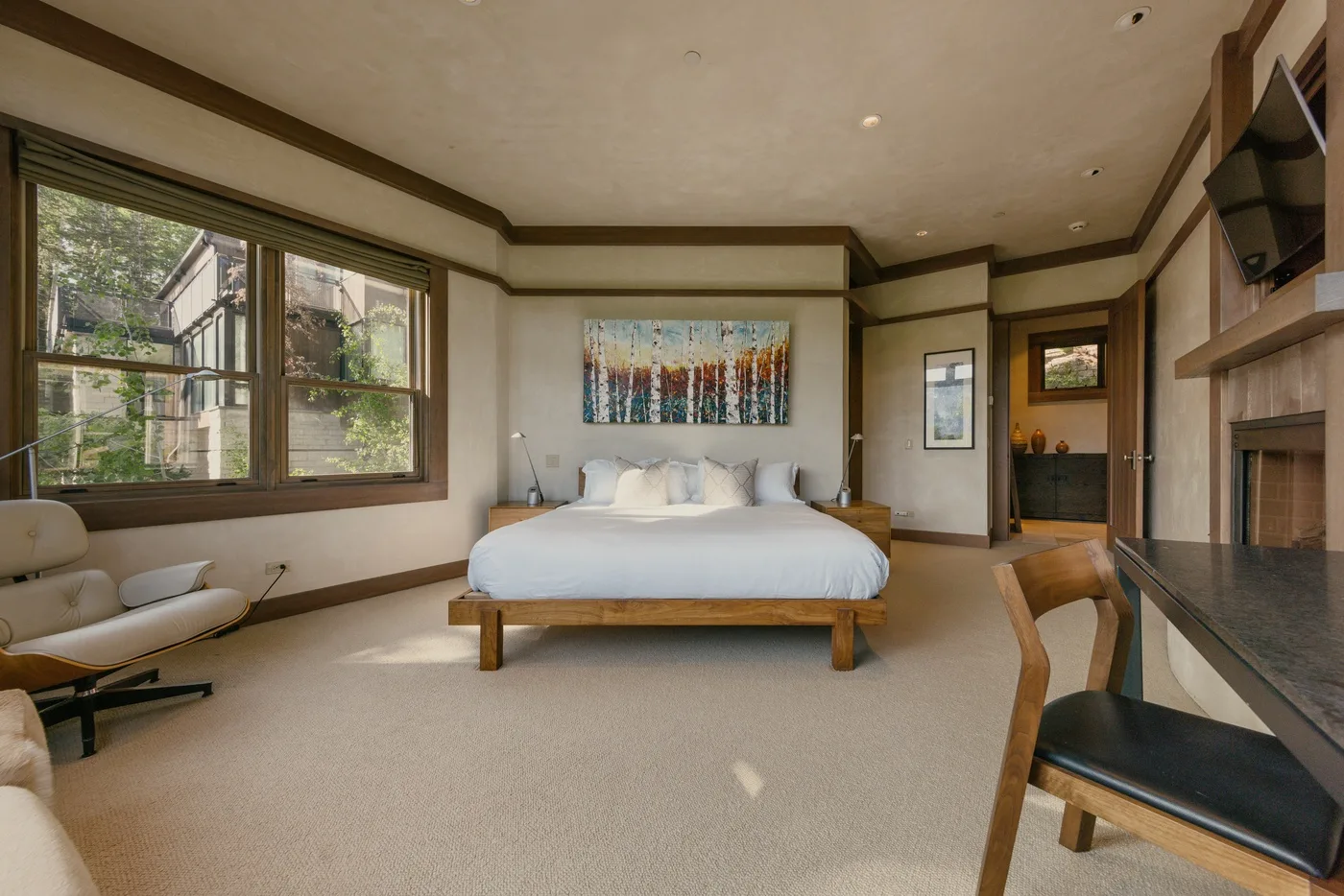 A bedroom with a bed, large windows, and a desk area.