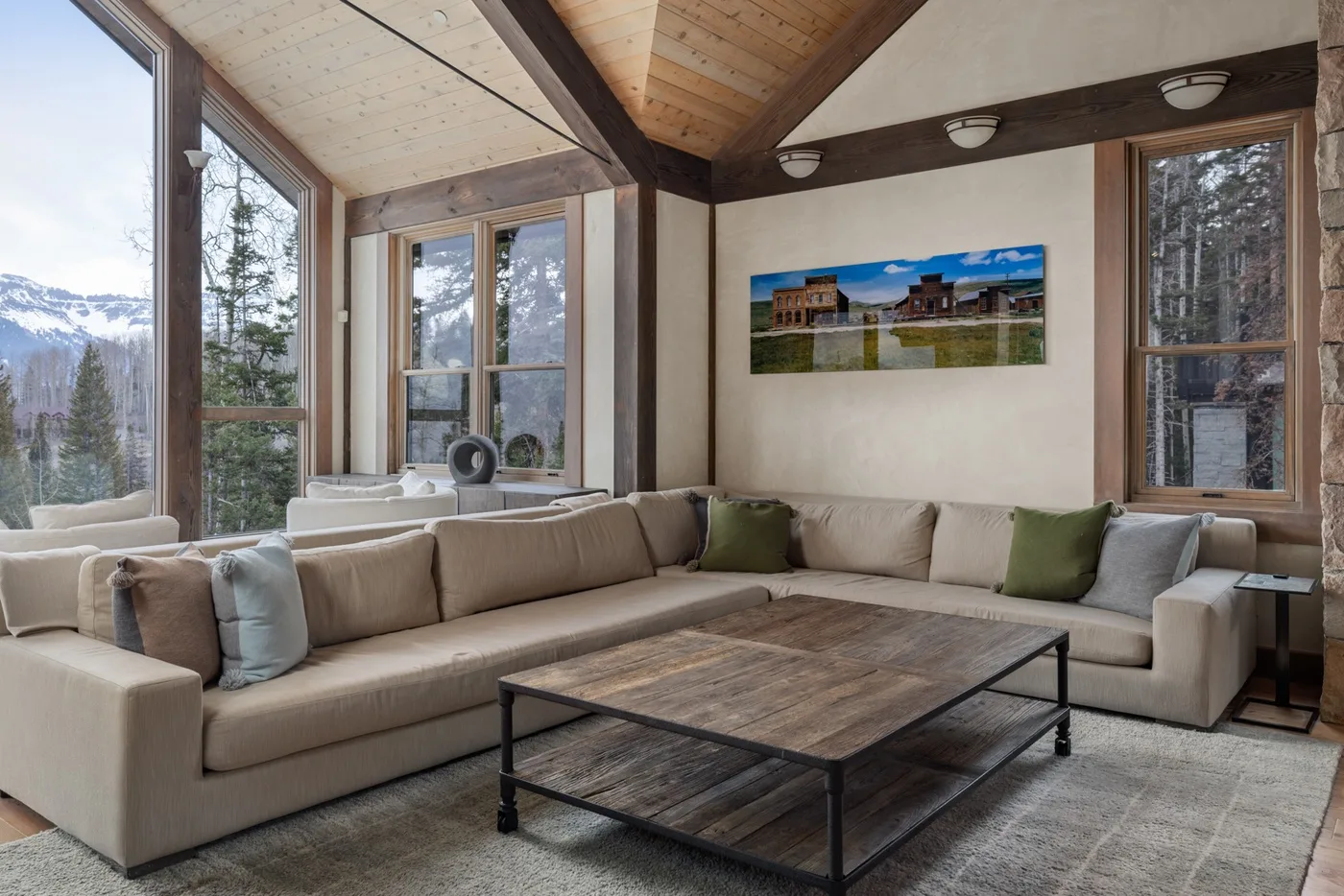 A bright living room with spacious seating and large windows overlooking a wooded landscape.