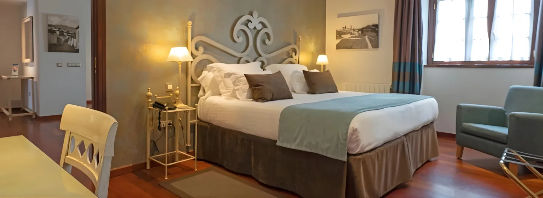 Habitación de hotel con una cama doble, lámparas de mesilla y un sillón.