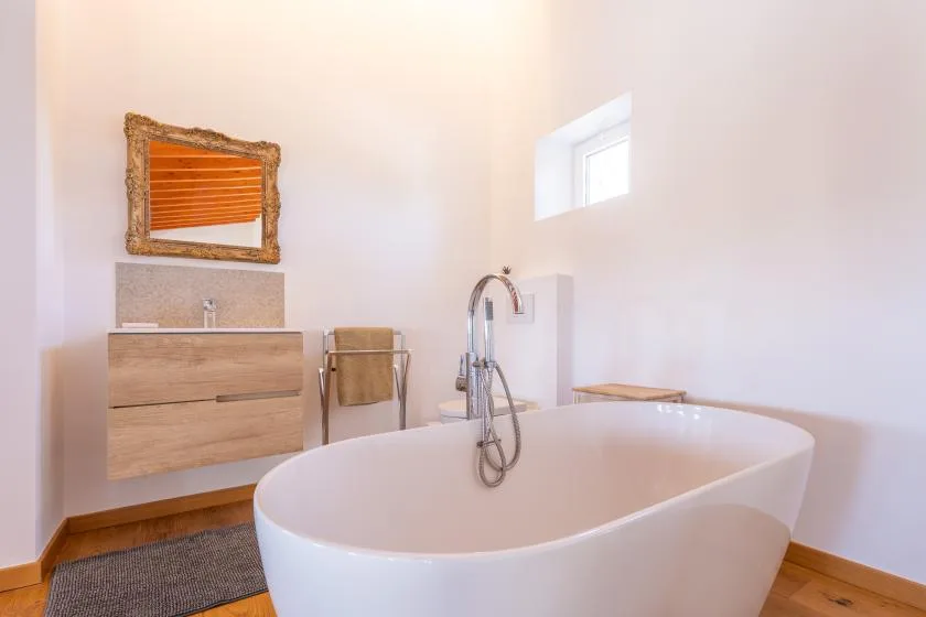 A bright bathroom features a freestanding bathtub and a wall-mounted vanity.