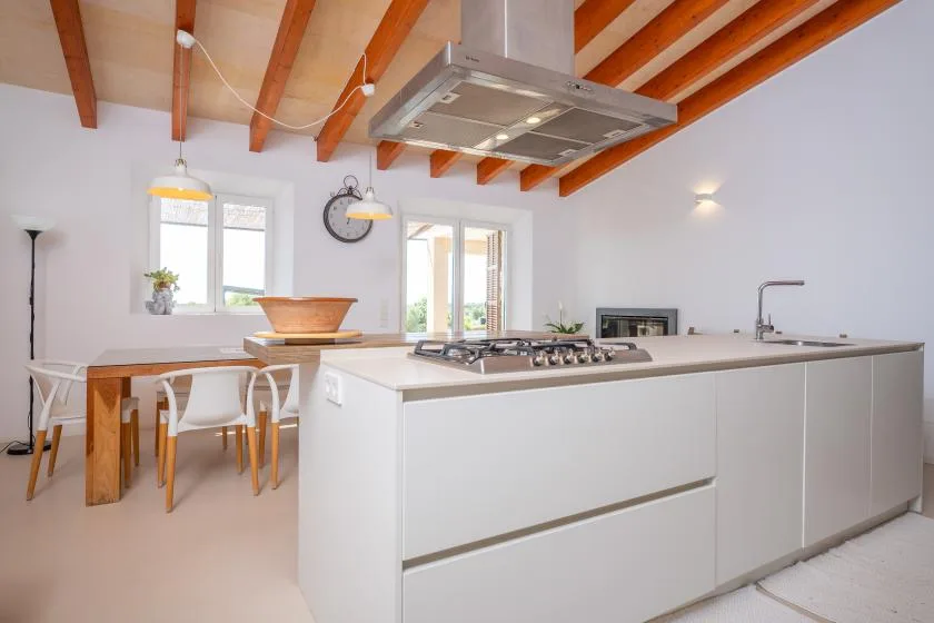 A bright kitchen with a large island and a dining table by the windows.