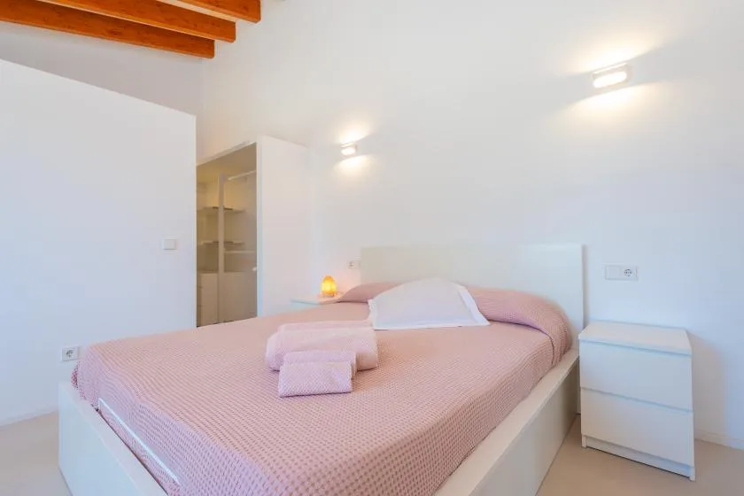 A bedroom with a pink bed and folded towels.