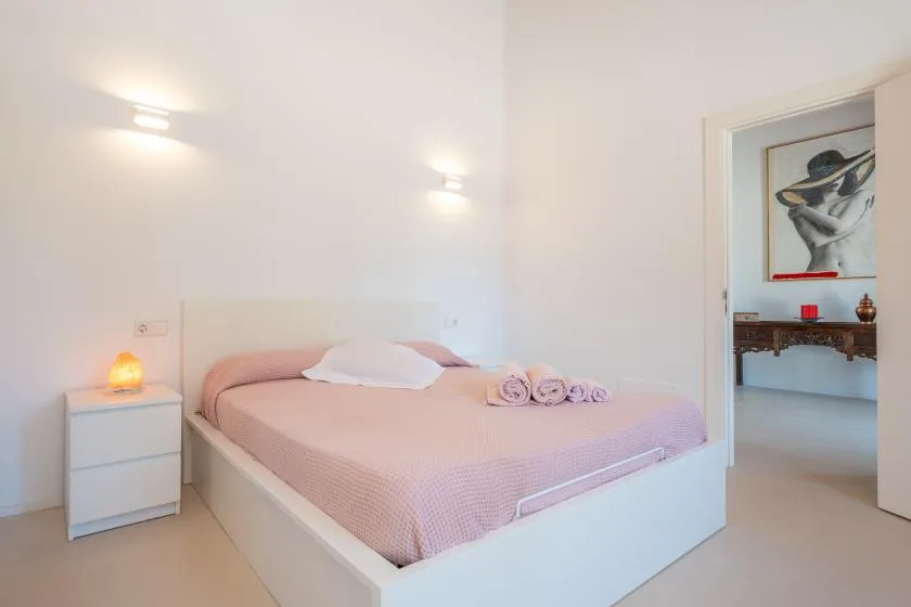 A bedroom with a double bed, bedside table, and a doorway to an adjoining room.