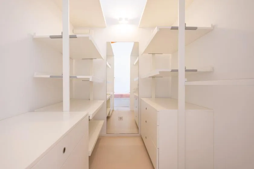 A bright walk-in closet with built-in shelving and drawers.